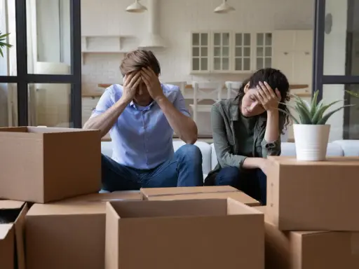 Couple overwhelmed by the stress of moving, surrounded by moving boxes.