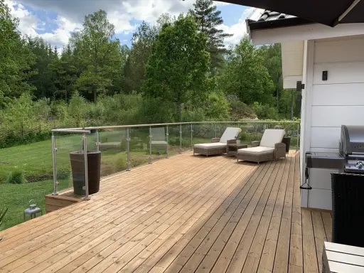 Träaltan med solstolar och grill. För att bevara träets skönhet, fundera på hur ofta olja altan.