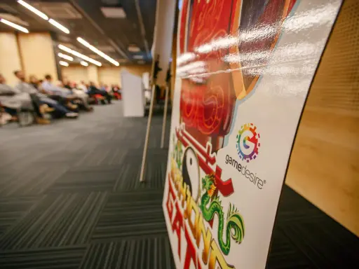 Na konferencji o grach planszowych, z bliska widać planszę z logo "gamedesire" i smoczym motywem.