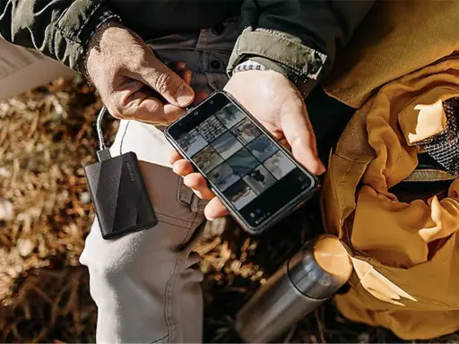 Un homme charge son téléphone avec une batterie externe, une aide précieuse pour comment organiser son téléphone et ses photos en voyage.