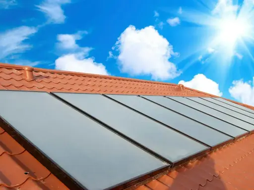 Fakta om solceller: Solpaneler på ett tegeltak fångar solens energi under en klarblå himmel med moln.