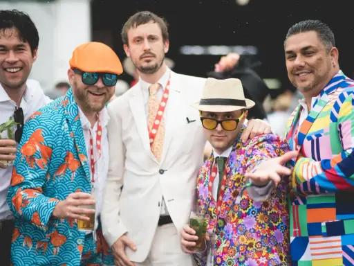 Men at the Kentucky Derby sport vibrant, patterned suits, showcasing bold fashion choices.