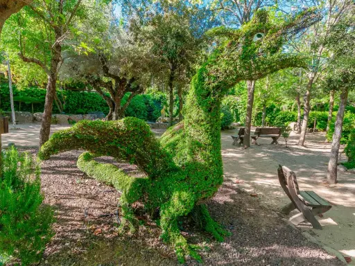 Un dragón de topiaria verde en un parque. Un lugar genial donde ver animales en Madrid, aunque este sea de plantas.