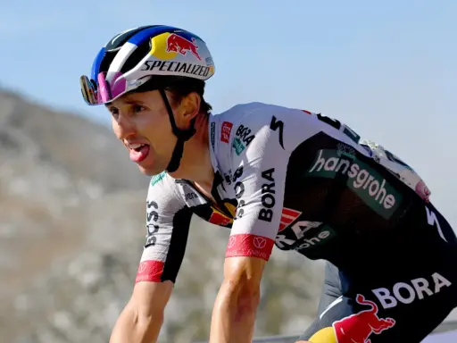 Radfahrer Jai Hindley kämpft sich mit herausgestreckter Zunge einen Berg hinauf, sein Helm trägt das Red Bull Logo.