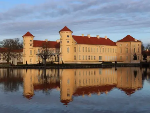 Das Schloss Rheinsberg spiegelt sich im Wasser. Die historische Altstadt von Rheinsberg zeigt sich von ihrer schönsten Seite.