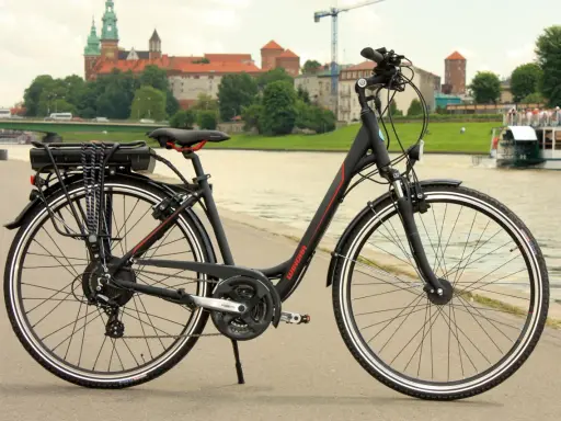 Rower z widocznym bagażnikiem i baterią, gotowy do konwersji na elektryczny. W tle zamek Królewski na Wawelu.