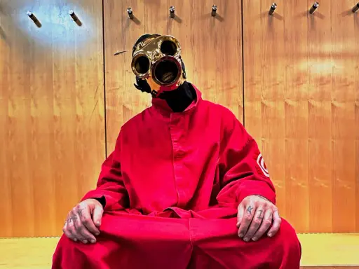 Sid Wilson i Slipknot sitter i en röd overall med en unik mask.