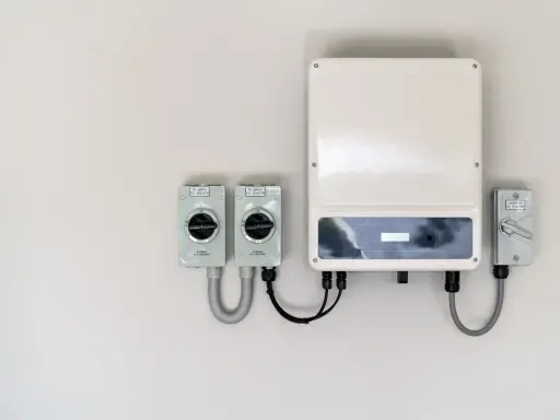 En vit vägg med en solcells-växelriktare och tre D.C. isolatorer. En del av systemet för att omvandla solenergi till el.