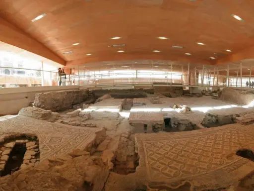 Resti archeologici della domus del chirurgo, con pavimenti a mosaico ben conservati sotto una moderna copertura in legno e vetro.