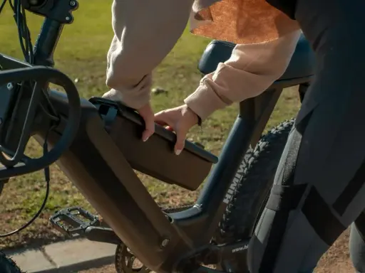 Osoba wyjmuje baterię z roweru elektrycznego, przygotowując się do ładowania.