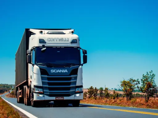 Camión Scania blanco en carretera soleada. Pensando en el coste del carnet de camión para conducir este gigante.