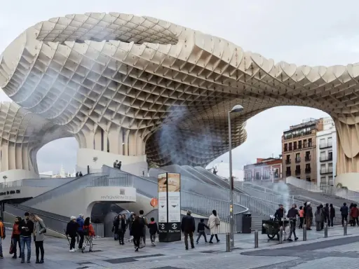 Ein Meisterwerk des Dekonstruktivismus: die Metropol Parasol in Sevilla. Menschen schlendern unter der organisch geformten Holzkonstruktion hindurch.