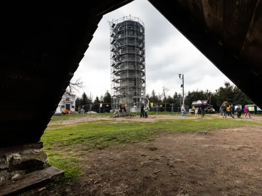 Wieża widokowa w budowie, obok pomnik. Turyści szukają informacji, jak dojechać do Wielkiej Sowy.