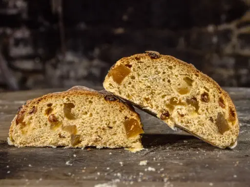 Deux tranches de pain au levain de gingembre, garnies de fruits confits, sur une table en bois rustique.
