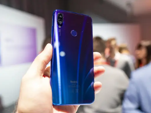 Błyszczący, niebieski tył telefonu Redmi 7 Pro z podwójnym aparatem 48MP i czytnikiem linii papilarnych, trzymany w dłoni.