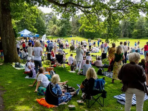 Midsommar i Slottsskogen samlar folk för picknick och gemenskap under trädens skugga.