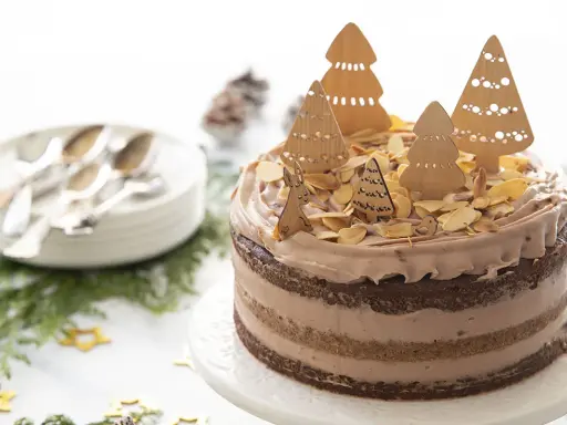 Gâteau au chocolat décoré d'arbres de Noël en bois, d'amandes effilées et d'un lapin.