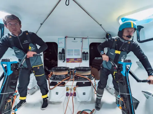 Deux marins concentrés sur le pont d'un bateau, prêts pour la course **Kerkena 6.1**.