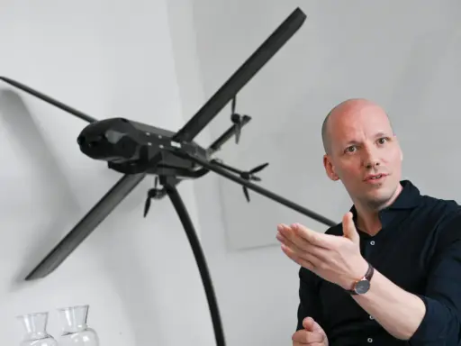 Mann erklärt ein Modell von lba drohnen, das auf einem Stativ steht.