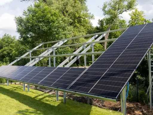 Instalacja fotowoltaiki na gruncie w ogrodzie. Panele słoneczne montowane na metalowej konstrukcji, gotowe do produkcji czystej energii.