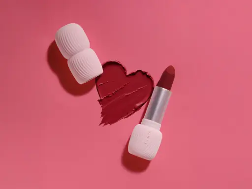 Un cuore di rossetto rosso, con un rossetto e un applicatore, mostra diversi tipi di rossetto.