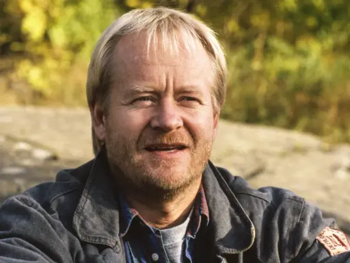 En leende svensk manlig skådespelare från 2000-talet, med blont hår och skäggstubb, bär en jeansjacka.
