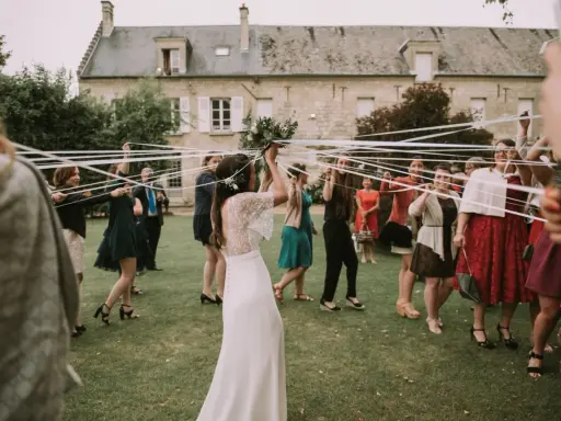 Novia con ramo de flores, rodeada de mujeres con cintas blancas, en el momento cuando se tira el ramo de novia.