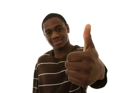 Un jeune homme souriant fait un pouce levé, signe qu'il n'y a pas de souci.