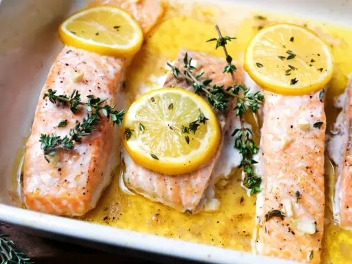 Saftiger Lachs mit Kartoffeln im Ofen, garniert mit Zitronenscheiben und frischem Thymian.