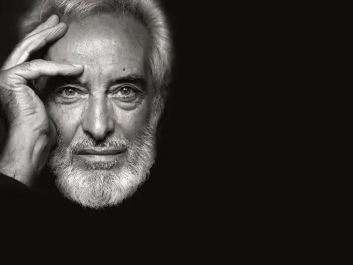 Ritratto in bianco e nero di un uomo anziano con barba bianca, mano sulla fronte. Un fotografo napoletano famoso cattura uno sguardo intenso.