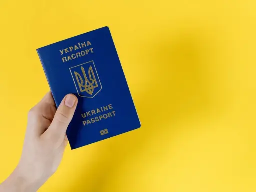 Dłoń trzyma niebieski paszport Ukrainy. Ważność dokumentu jest kluczowa dla statusu ukr do kiedy.