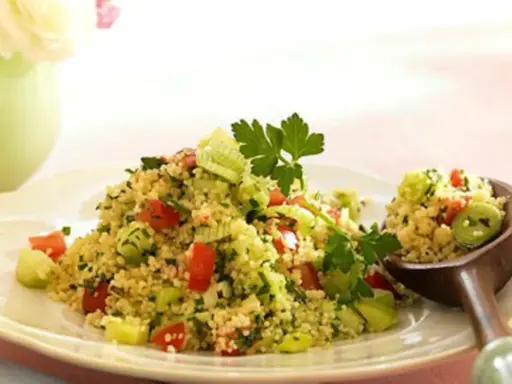 Frischer Couscous-Salat mit Tomaten, Gurken und Kräutern, garniert mit Petersilie. Ein Löffel voller Genuss.