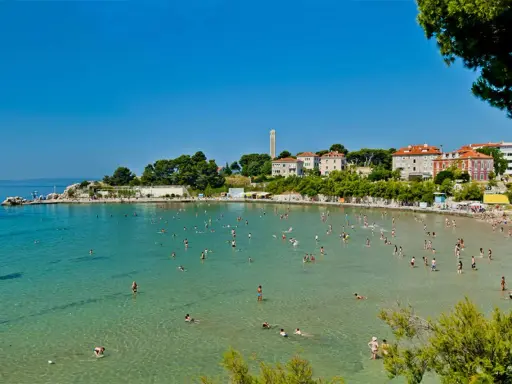 Una giornata di sole sulle spiagge Croazia, con gente che nuota e si rilassa nell'acqua cristallina.