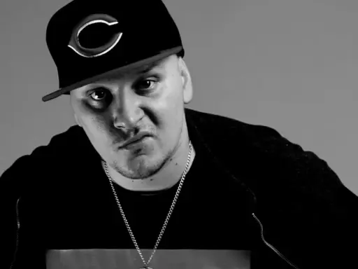 Mroczny ruby raper w czapce z daszkiem i łańcuchem, zamyślony.