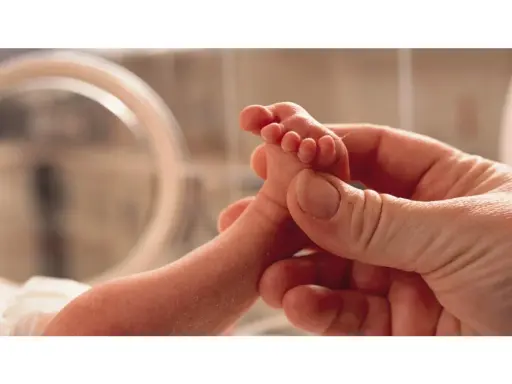 Un piedino di neonato tenuto da una mano adulta. Un'immagine che evoca la delicatezza e l'importanza della valutazione Apgar, un test per valutare le condizioni del neonato alla nascita.