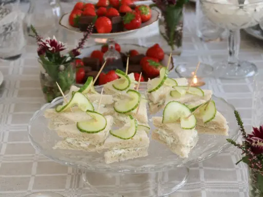 Smörgåsar med gurka och krämig fyllning, perfekta för ett afternoon tea recept. Jordgubbar och choklad i bakgrunden.