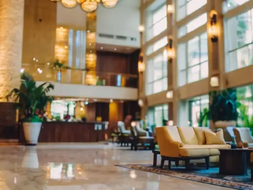 Eleganckie lobby hotelu 10 gwiazdkowego z marmurową podłogą, wygodnymi sofami i bujną roślinnością.