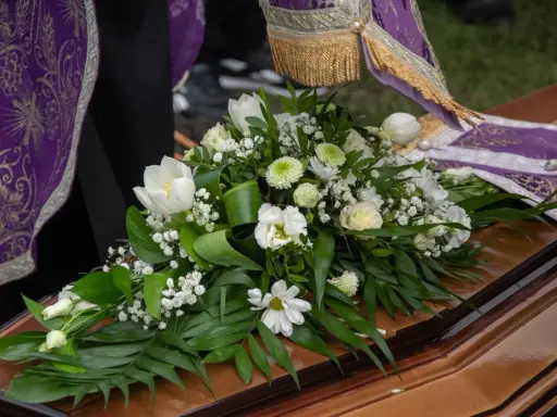 Białe lilie i inne kwiaty na trumnie, symbol pożegnania. Uroczysty bukiet na pogrzeb.