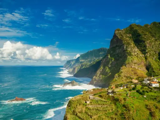 Grüne, steile Küsten mit kleinen Häusern, die sich an den Hang schmiegen. Das azurblaue Meer brandet an Felsen. Ja, Madeira in der EU bietet diese atemberaubende Aussicht.