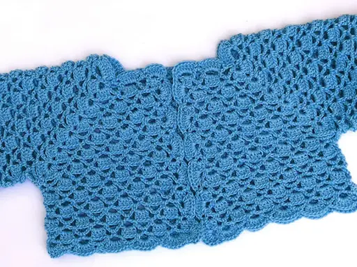 Bolero crochet azul con un delicado patrón de escamas y borde ondulado.