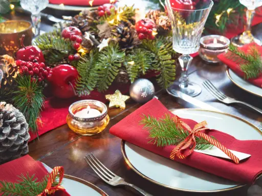Vackert dukat på julbordet med röda servetter, granris och julgranskulor.