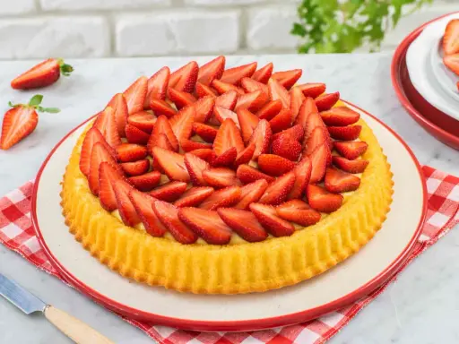 Una deliziosa crostata morbida alle fragole, con la sua base dorata e un abbondante strato di fragole fresche affettate.