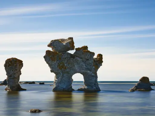 Raukar i havet vid Fårö, Gotland. En fantastisk vy att se på Gotland, med stenformationer som reser sig ur det blå vattnet under en molnig himmel.