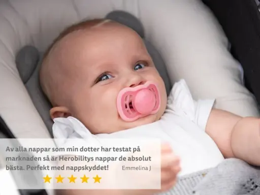 Söt bebis med rosa napp i munnen, som verkar nöjd. En recension lyfter fram nappens kvalitet.