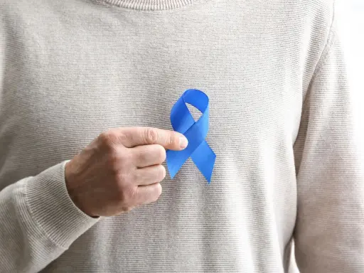 Mężczyzna trzyma niebieską wstążkę symbolizującą świadomość raka prostaty. Rozważamy usunięcie prostaty skutki.