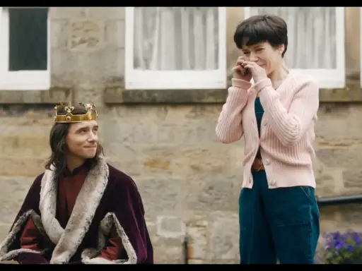 Un re con la corona e la pelliccia, forse il protagonista di "the lost king film", guarda una donna che ride con le mani sul viso.