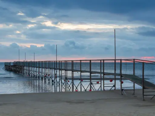 Molo di Rimini Rivazzurra al tramonto, con cielo nuvoloso e mare calmo.
