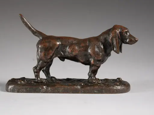 Une sculpture en bronze d'un chien basset hound, une des œuvres d'art de Antoine-Louis Barye, sur un socle imitant le sol.