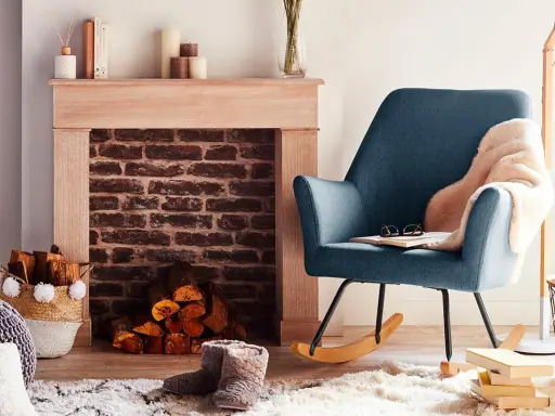 Un fauteuil bleu confortable invite à la détente près d'une cheminée en briques, créant un coin cheminée cocooning parfait pour lire.
