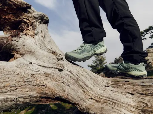 Zielone buty trekkingowe na pniu drzewa. Idealne na górskie wędrówki, zapewniające stabilność i komfort.